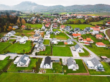 Aerial view, drone flying over new housing development in the country side. Family homes in the suburbs surrounded with forest and green fields. 