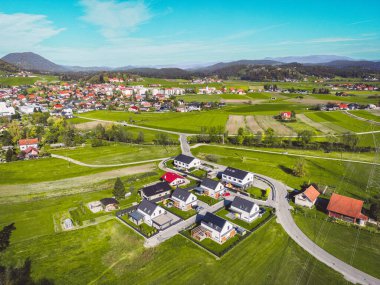 Aerial view, drone flying over suburban community in the country side. Family homes in the suburbs surrounded with forest and green fields. 
