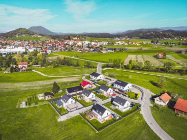 Aerial view, drone flying over suburban community in the country side. Family homes in the suburbs surrounded with forest and green fields. 
