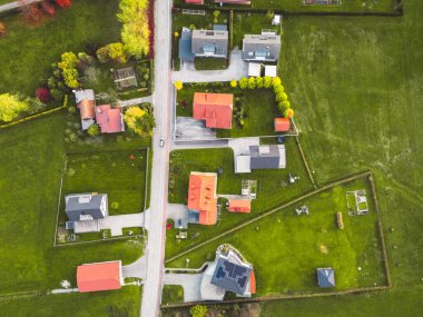 Aerial view, drone flying over suburban community in the country side. Family homes in the suburbs surrounded with forest and green fields. 
