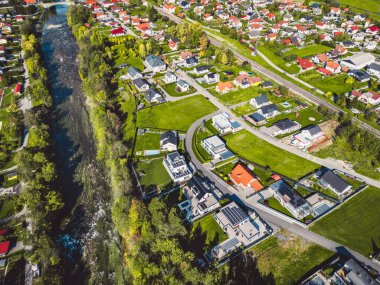 Aerial view, drone flying over suburban community in the country side. Family homes in the suburbs surrounded with forest and green fields. 