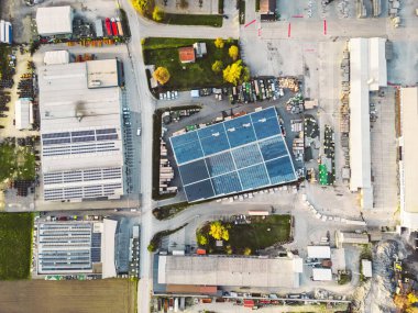 Aerial view of a factory, warehouse facility in the suburbs with roof top covered with solar panels. High quality photo