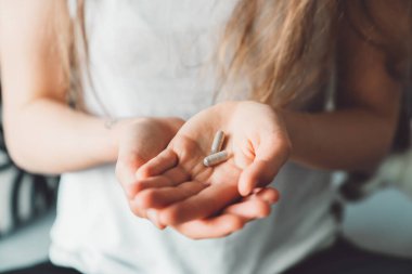 Gülümseyen beyaz bir kadın sabah ilavelerini alıyor, evinde bir bardak suyla vitamin hapları alıyor. Yüksek kalite fotoğraf