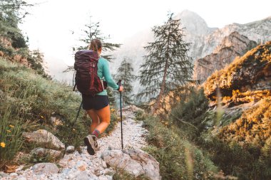 Beyaz bir kadın sabahın erken saatlerinde sırt çantasıyla Avrupa Alplerinde güzel patikada yürüyüş yapıyor. Seyahat ve macera konsepti. Yüksek kalite fotoğraf