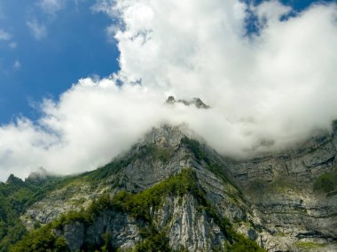 Beyaz bulutlarla kaplı dik dağ..