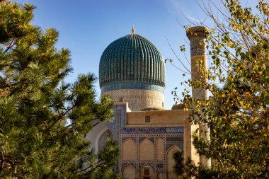 Her iki tarafı ve ortasını kaplayan ağaç üzerinde güzel bir kubbe olan tarihi bir bina Amir Temur Anıtmezar, medrese, Semerkand, sonbahar..