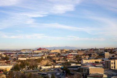 Dağdan şehrin panoramik manzarası, uzaklarda karla kaplı güzel bir dağ.