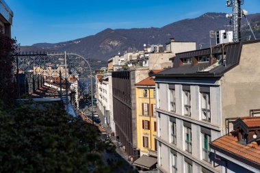 A city street with a view of the mountains in the background. The buildings are tall and the street is busy with people walking around clipart