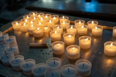 Küçük bardaklarda yanan bir sürü mumla dolu bir masa. Mumlar yanıyor ve görüntünün havası huzurlu ve huzurlu.