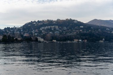 Arka planda şehir olan sakin bir göl. Su durgun ve gökyüzü bulutlu.