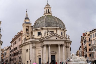 Tepesinde kubbe olan büyük beyaz bir bina. Bina, içinde beyaz bir aslan heykeli olan bir avluyla çevrilidir. Gökyüzü bulutlu ve atmosfer sakin ve huzurlu.