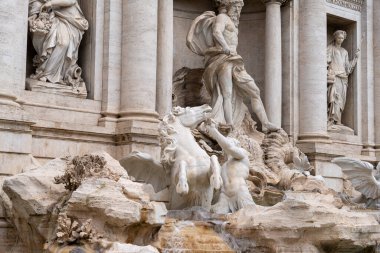 Bir at heykeli ve bir adam binanın önünde. At heykeli sahnenin ortasında ve adam da sağ tarafta.