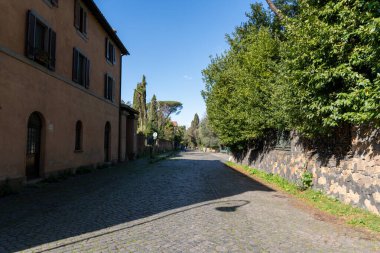 Tuğladan yolu olan sessiz bir cadde ve balkonlu bir bina. Sokaklar boş ve gökyüzü temiz.