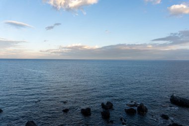 Okyanus sakin ve gökyüzü açık. Su koyu mavi bir renktir.