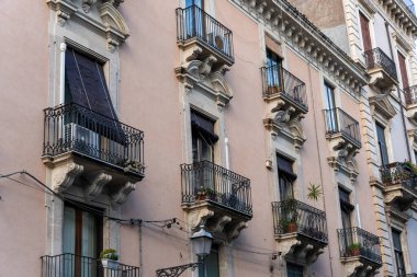 Balkonları ve balkon korkulukları olan bir sıra daire. Balkonlar saksı bitkileriyle süslenmiş.