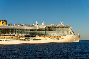 Büyük bir yolcu gemisi okyanusta yelken açıyor. Gemi beyaz ve sarıdır ve sudaki en büyük gemidir.