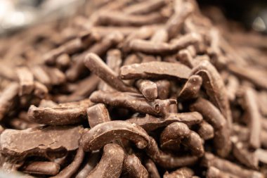 Bir yığın çikolata kaplı çubuk. Çubukların hepsi farklı boyutlarda ve şekillerde. Yığın kahverengi ve lezzetli görünüyor.