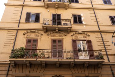 Üzerinde balkon ve saksı bitkisi olan bir bina. Balkonda korkuluk ve birkaç saksı bitkisi var.