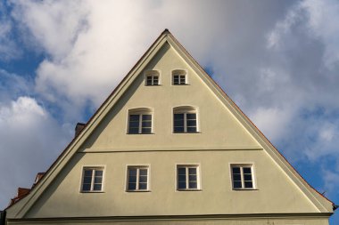 Üçgen çatılı ve pencereli beyaz bir bina. Bina yüksek ve bir sürü penceresi var.