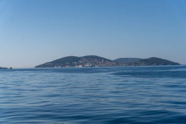 Uzakta küçük bir adası olan sakin mavi bir okyanus. Su durgun ve gökyüzü berrak.