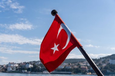 Üzerinde yıldız ve hilal olan kırmızı ve beyaz bir bayrak. Bayrak gökyüzünde dalgalanıyor