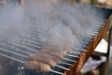 Izgara etle dolu ve duman yükseliyor. Sahne, hazirlanmakta olan lezzetli yemegin heyecanli ve beklentisidir.