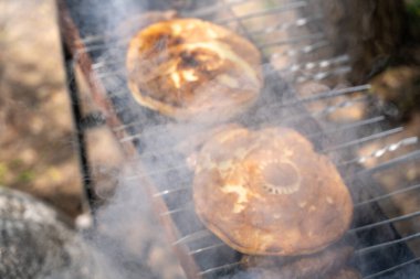 İki krep ızgarada pişiyor ve tavadan duman yükseliyor. Krepler altın sarısı ve lezzetli görünüyor. Sahnenin sıcak ve davetkar bir atmosferi var.