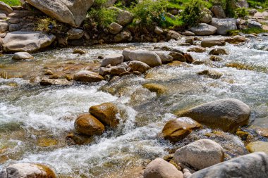 Büyük kayalar arasında bir su akıntısı akar. Sahne huzurlu ve sakin, su kayaların üzerinden geçerken sakinleştirici bir ses çıkarıyor.