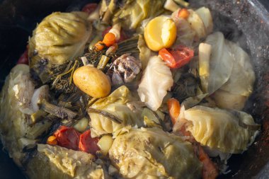 Patates, havuç ve lahana dahil çeşitli sebzelerle dolu bir tencere yemek. Yemek kaynıyor ve o doyurucu bir yemek.