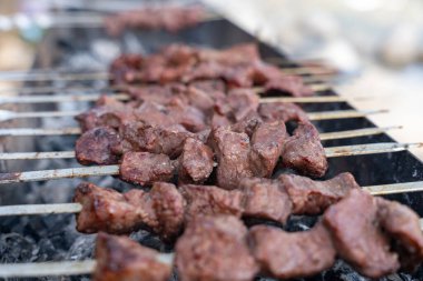 Izgaradaki et şişleri yakın plan. Et kahverengidir ve pişmiştir.