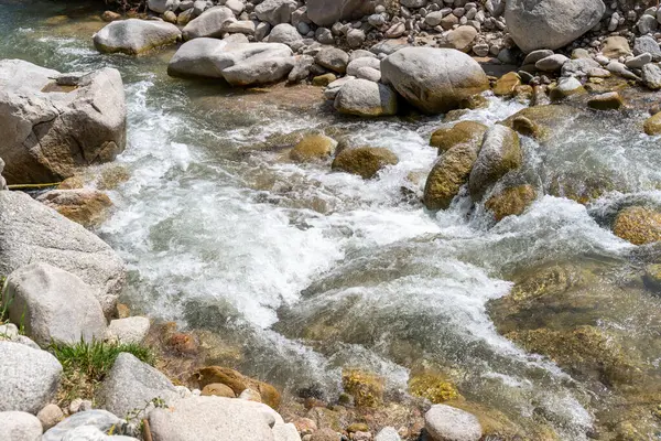 Büyük kayalar arasında bir su akıntısı akar. Sahne huzurlu ve sakin, su kayaların üzerinden geçerken sakinleştirici bir ses çıkarıyor.