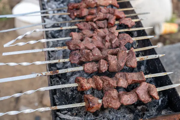 Izgarada bir et şişi pişiyor. Et kahverengi ve o iyi pişmiş.