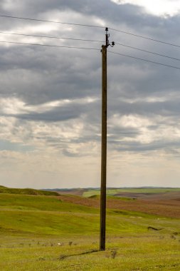 Tepesinde bulutlu bir gökyüzü olan bir tarlada uzun tahta bir direk duruyor. Direk çıplak ve üzerinde kablo yok. Sahne sakin ve huzurlu, uzun bir direk uçsuz bucaksız açık alanda tek başına duruyor.