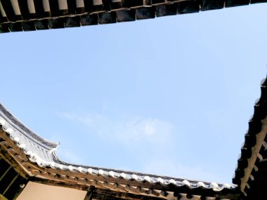 Gökyüzü mavi ve güneş parlıyor. Çatı eğimli ve güneş çatıda parlıyor.