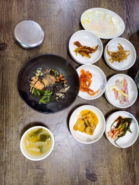 İçinde bir kase çorba da dahil bir sürü yiyecek olan bir masa. Sahne davetkar ve sıcak, sanki aile veya arkadaşlar arasında bir yemek paylaşılıyor gibi.