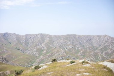 The mountain range is covered in rocks and grass. The sky is clear and blue. The view is breathtaking and serene clipart