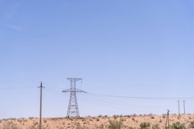 Bir güç hattı kulesi çölün ortasında. Gökyüzü açık ve mavi