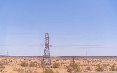 Yüksek bir güç kulesi çöl manzarasıyla çevrilidir. Gökyüzü açık ve mavidir, ve uzakta uçan birçok kuş vardır. İzolasyon kavramı ve uçsuz bucaksızlığın yanı sıra doğanın gücü