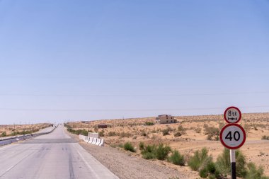 Üzerinde 40 yazan tabelası olan bir yol. Yol boş ve uzakta bir ev var.