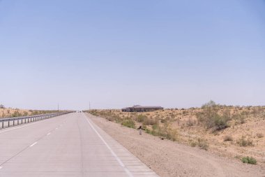 Uzakta bir bina olan bir yol. Yol boş ve gökyüzü temiz.
