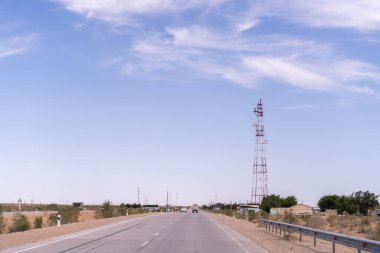 Uzakta yüksek kulesi olan bir yol. Gökyüzü açık ve mavi. Yolda hiç araba yok.