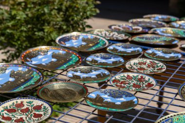 Mavi gökyüzü ve bulutlar da dahil olmak üzere çeşitli tasarım ve renklere sahip bir tabak koleksiyonu. Tabaklar bir rafta sergileniyor ve görüntünün genel havası yaratıcılıktan kaynaklanıyor.