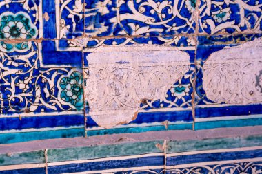 Mavi çiçek desenli mavi ve beyaz bir fayans duvarı. Duvar eski ve biraz hasar görmüş.