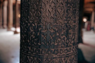 Üzerinde karmaşık oymalar olan tahta bir sütun. Oymalar çok detaylı ve sütun çok eski.