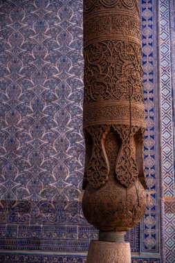 Mavi ve beyaz arka planı olan tahta bir sütun. Sütun karmaşık tasarımlarla oyulmuştur. Mavi ve beyaz arka plan resme huzur ve sükunet hissi veriyor.