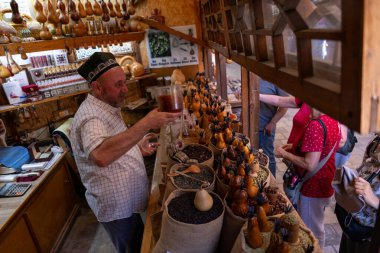 Bir adam mağazadaki bir müşteri için içki dolduruyor. Mağaza çok sayıda armut da dahil olmak üzere çeşitli eşyalarla dolu. Mağazada birkaç kişi var.