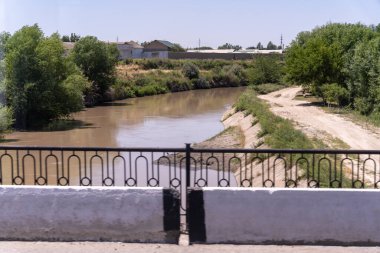 Nehrin kenarında bir çit var. Çit siyah ve beyaz.