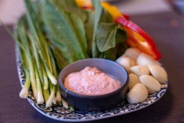 Bir tabak sebze ve sos, mavi ve beyaz tabakla.