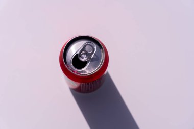 Bir kutu soda açılır ve beyaz bir yüzeyde durur. Kutu boş ve kapağı hala açık.