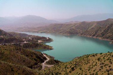 Arkasında yeşil bir yamaç olan güzel bir dağ gölü. Göl sakin ve huzurlu. Çevresindeki manzara da sakin ve resim gibi.